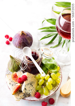 Assortment of cheese, berries and grapes with red wine in glasses on stone background. Copy space 56872035