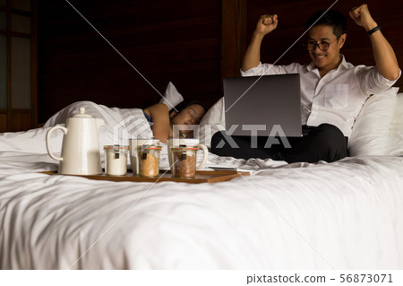 Businessman with hands up while working on laptop in bed celebrating Victory. Businessman with hands up while working on laptop in bed celebrating Victory. 56873071