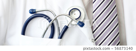 Male GP wearing tie holding stethoscope in smock pocket Male GP wearing tie holding stethoscope in smock pocket 56873140