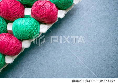 Balls of colored red and green yarn in a paper egg 56873156