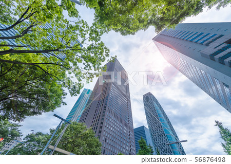新宿摩天大樓和新鮮的綠樹在多雲的天空 新宿摩天大樓和新鮮的綠樹在多雲的天空 56876498