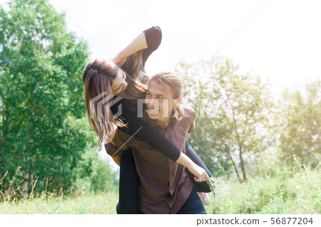 Fun loving couple on a walk in nature. Guy's got a girl on his back. 56877204