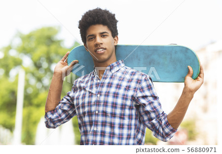Handsome african teen posing with modern skateboard in hands 56880971