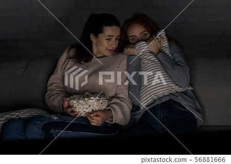 Teenage girls watching horror movie with popcorn Teenage girls watching horror movie with popcorn 56881666