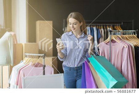 Smiling shopping woman with bags chatting on phone Smiling shopping woman with bags chatting on phone 56881677