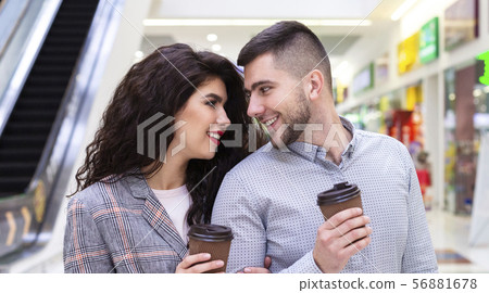 Young couple drinking coffee to go after long shopping Young couple drinking coffee to go after long shopping 56881678