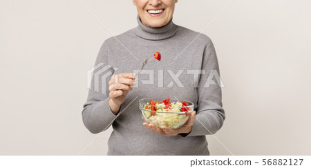 Healthy eating. Happy aged woman holding bowl of vegetable salad 56882127
