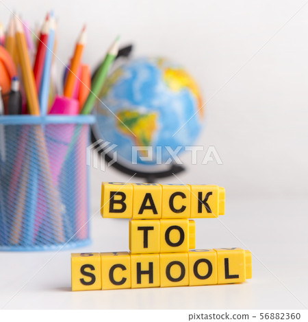 Back to school text on yellow cubes, school supplies on white 56882360