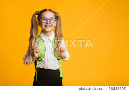 Cute First-Grade Elementary Student Smiling At Camera Over Yellow Background Cute First-Grade Elementary Student Smiling At Camera Over Yellow Background 56882805