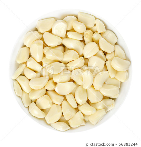 Peeled garlic cloves in white bowl over white 56883244