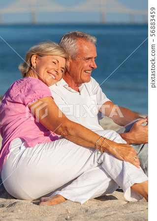 Senior Couple Sitting Laughing Smiling on a Beach Senior Couple Sitting Laughing Smiling on a Beach 56883459