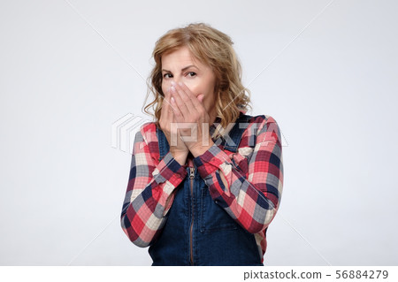 Mature caucasian woman covering her mouth with hands. 56884279