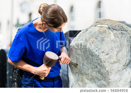 Stonemason working on boulder with sledgehammer and iron Stonemason working on boulder with sledgehammer and iron 56884958