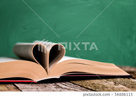 Open book and pages folded in the shape of a heart 56886115
