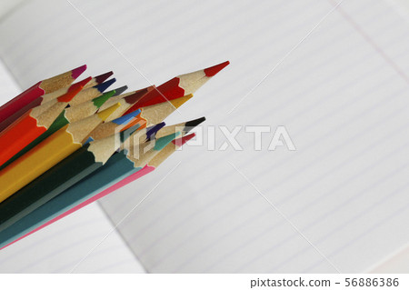 Colored pencils lie on a striped notebook. 56886386