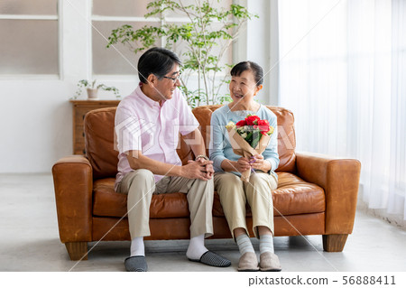 Senior couple presenting a bouquet Senior couple presenting a bouquet 56888411