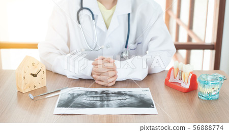 Dentist with dental implant model. 56888774