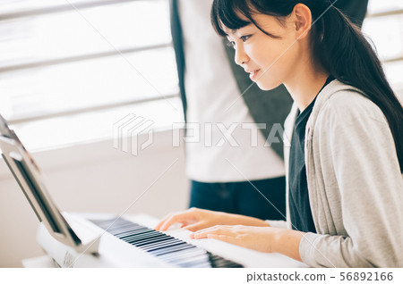 Girls playing electronic piano 56892166
