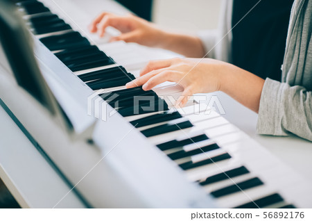 Girls playing electronic piano 56892176