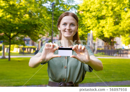 Blonde girl in a summer green dress with a plastic card in a park outdoors. Blonde girl in a summer green dress with a plastic card in a park outdoors. 56897938