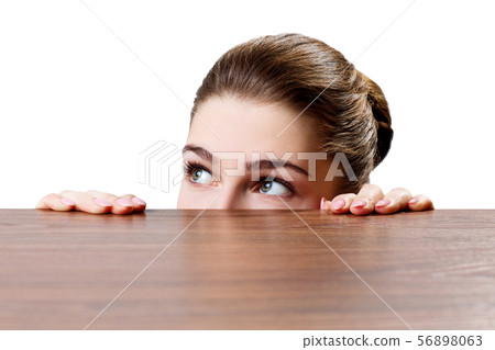 Woman peeping under the edge of wooden table. 56898063