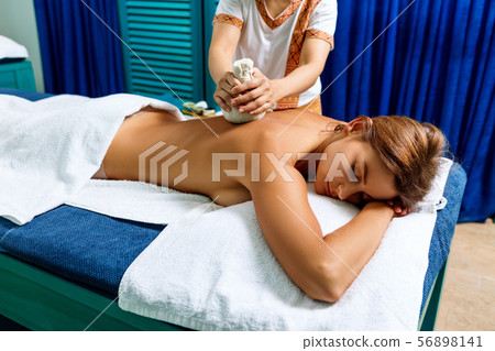 Woman getting massage with hot herbal bags. Woman getting massage with hot herbal bags. 56898141