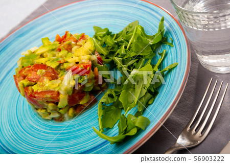 Delicious salad guacamole with fresh tomatoes and arugula at plate Delicious salad guacamole with fresh tomatoes and arugula at plate 56903222