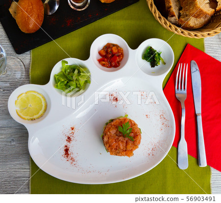 Tasty tartar from salmon served with vegetables and lemon Tasty tartar from salmon served with vegetables and lemon 56903491
