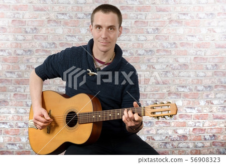 man with an acoustic guitar in his hands 56908323