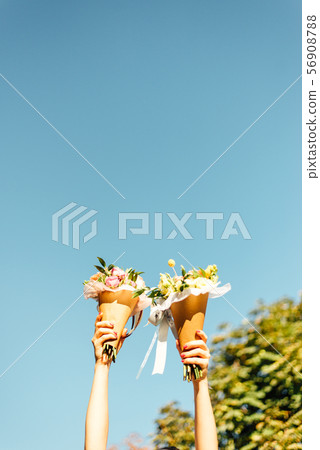 Bouquets of flowers in two hand and blue sky. Women family lgtb. Wedding day. Florist. Copy space Bouquets of flowers in two hand and blue sky. Women family lgtb. Wedding day. Florist. Copy space 56908788