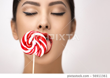 Fashion Portrait of Asian Woman with Lollipop in Studio 56911361