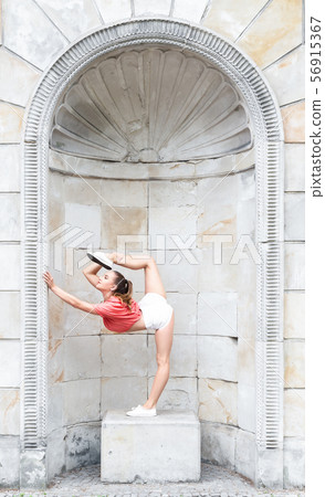 Beautiful gymnastic woman stretching outdoors Beautiful gymnastic woman stretching outdoors 56915367