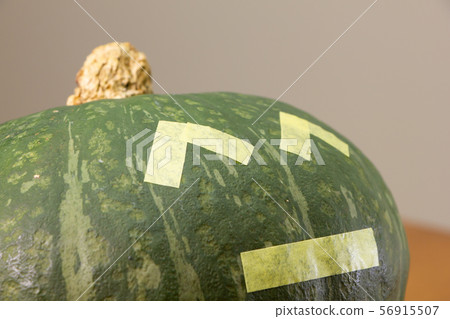 A pumpkin decorated with Halloween jack-o-lantern style masking tape. 56915507