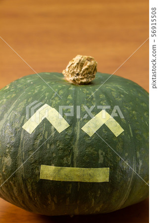 A pumpkin decorated with Halloween jack-o-lantern style masking tape. 56915508