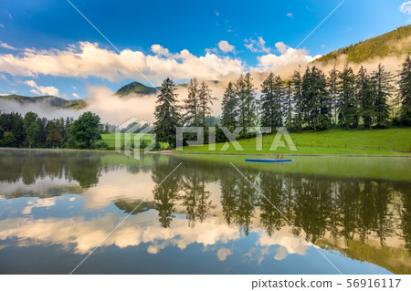 Reflection sky and trees in calm lake in Mountains 56916117