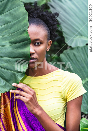 African girl hid her face behind big green leaf African girl hid her face behind big green leaf 56921309