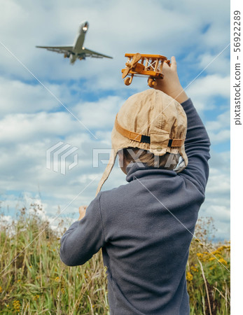 cute little boy in a pilot's suit is playing with a toy plane near the airport cute little boy in a pilot's suit is playing with a toy plane near the airport 56922289