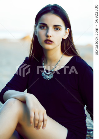 young pretty brunette girl with long hair waiting alone on sand at seacoast, lifestyle people 56922330