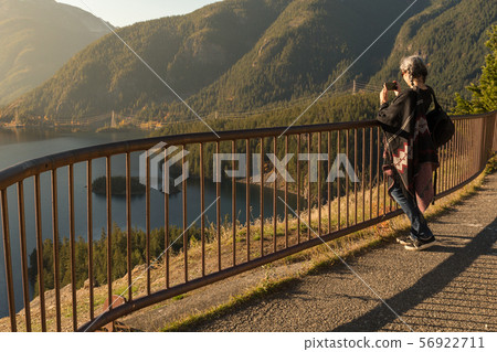 A young woman with white hair takes photographs with her smartphone of Diablo Lake, in North 56922711