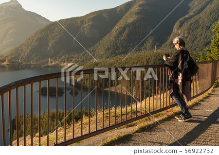 A young woman with white hair takes photographs with her smartphone of Diablo Lake, in North 56922732