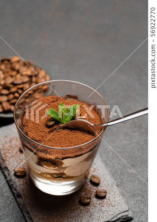 Portion of Classic tiramisu dessert in a glass cup on dark concrete background 56922770