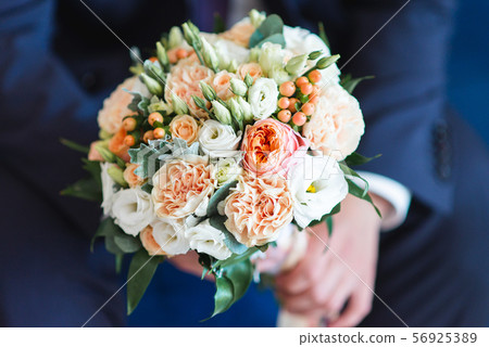 Elegant wedding bouquet in groom hand, beautifully decorated flowers closeup Elegant wedding bouquet in groom hand, beautifully decorated flowers closeup 56925389