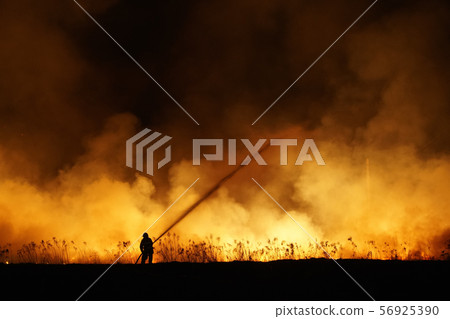 Silhouette of fireman fighting bushfire at night, man against the fire. Silhouette of fireman fighting bushfire at night, man against the fire. 56925390