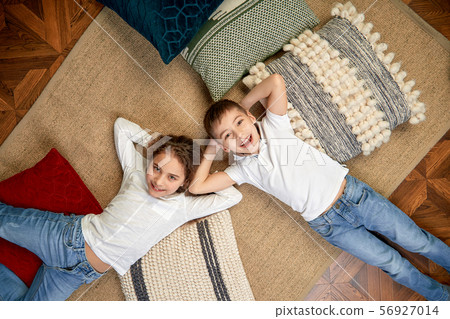 Beautiful children a boy and a girl lie on the floor and look at the camera. The concept of 56927014