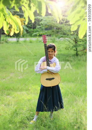 Asian school girl playing the guitar on the lawn , Asian school girl playing the guitar on the lawn , 56938099