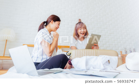 happy couple friend planing for travel sommer vacation.asia woman looking tablet and notebook, luggage, map, hat on bed.girl booking hotel or flight ticket or insurance online. happy couple friend planing for travel sommer vacation.asia woman looking tablet and notebook, luggage, map, hat on bed.girl booking hotel or flight ticket or insurance online. 56938747