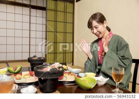 A young woman who is pleased to see a hot spring inn dinner GoTo Travel Campaign 56943132
