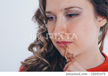 portrait of a girl with a violin key in her hands on a white background. The concept of advertising musical instruments, fashion, symbols 56945479