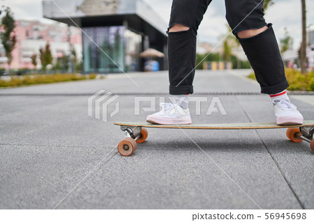Image of legs of woman in black jeans riding skateboard on street in city Image of legs of woman in black jeans riding skateboard on street in city 56945698
