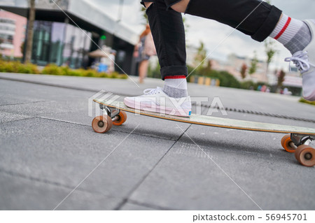 Image of legs of woman riding skateboard on street in city Image of legs of woman riding skateboard on street in city 56945701